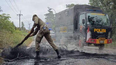 Petugas membersihkan sisa pohon dan ban yang dibakar warga di Pulau Rempang