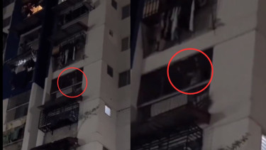 Perempuan bergaun putih tertawa dan meronta-ronta dari balkon apartemen.