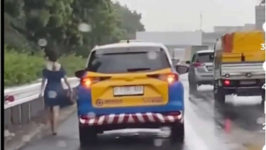 Wanita Jalan Kaki Sendirian Saat Hujan di Tol Jakarta Merak