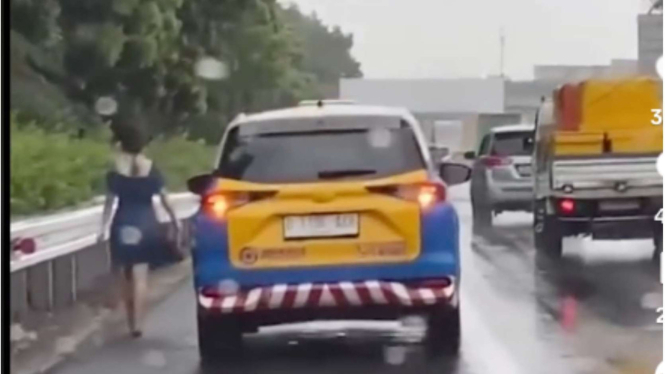 Wanita Jalan Kaki Sendirian Saat Hujan di Tol Jakarta Merak