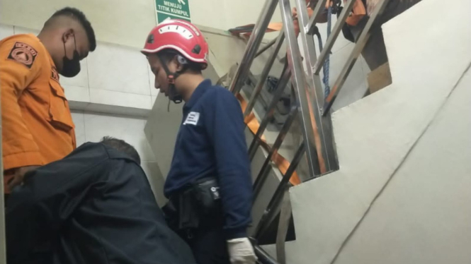 Petugas saat mengevakuasi tubuh korban yang tertimpa brankas di Surabaya. (Istimewa)