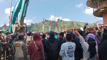 Warga mengadang alat berat meminta Satpol PP membongkar bangunan Asep Stroberi. 
