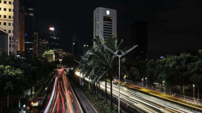 Sejumlah kendaraan melintas saat pemadaman lampu penerangan jalan di Jakarta.
