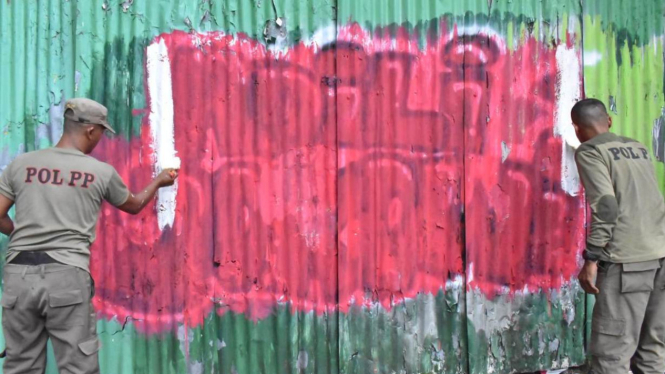 Petugas Satpol PP menghapus dan mengecat ulang coretan 'Adili Jokowi' di Kota Surabaya. (Foto: Dokumen Pemkot Surabaya)