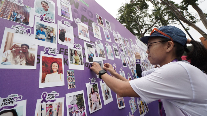 Peserta ajang lari MRCCC Run For Hope 2025 menempel foto di Wall of Warriors