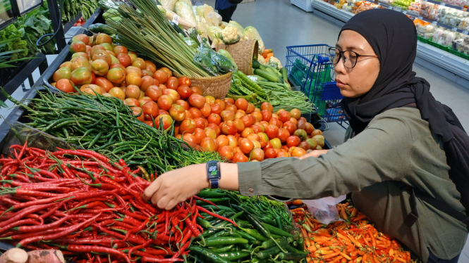 Seorang ibu rumah tangga memilah cabai merah di pasar swalayan.