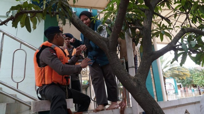 Brimob mengevakuasi warga korban banjir.