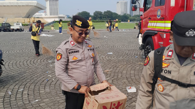 Petugas kepolisian yang ikut membantu bersih-bersih usai acara May Day di Lapangan Silang Monas, Jakarta Pusat pada Kamis 1 Mei 2025. (Doc. Polri)