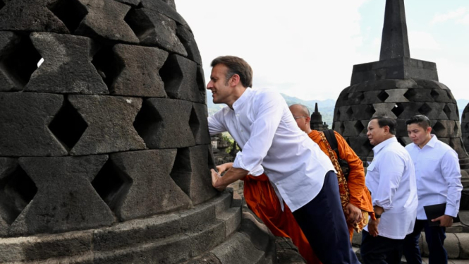 Presiden Prancis Emmanuel Macron saat mencoba menggapai patung Budha dalam Stupa di atas Candi Borobudur (sumber foto: Cahyo - Biro Pers Sekretariat Presiden)