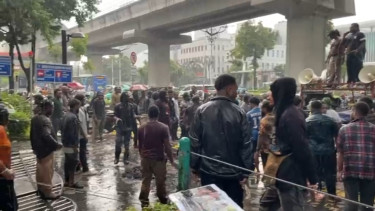 Puluhan massa aksi yang bertahan ditengah hujan deras di depan Kantor Kementerian HAM RI