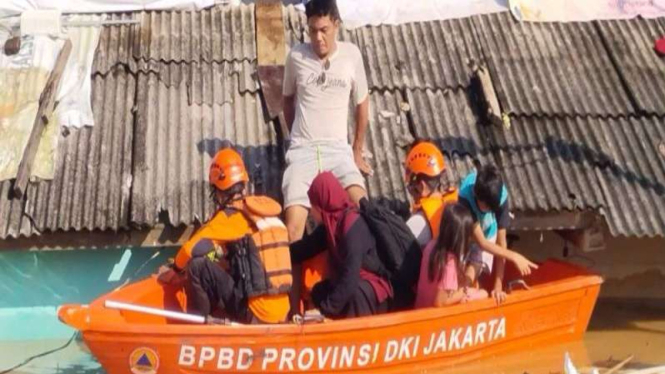 Petugas saat mengevakuasi warga terdampak banjir di Jakarta, Minggu (6/7/2025).