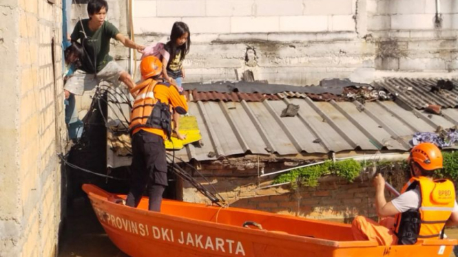 Petugas mengevakuasi warga yang terjebak banjir di Jakarta, Minggu (6/7/2025). 