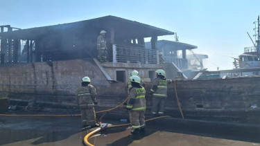 Petugas Damkar memadamkan kebakaran pada kapal nelayan di Dermaga Muara Baru